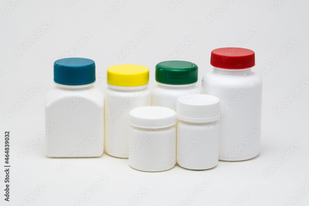 White plastic pill jars on a white background. Multi colored lids. Isolated White plastic pill jars on a white background. Multi colored lids. Isolated