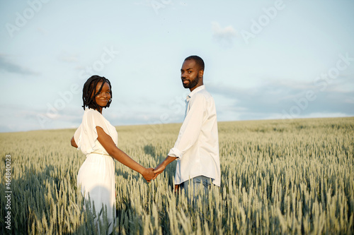 Young black couple walking through green field