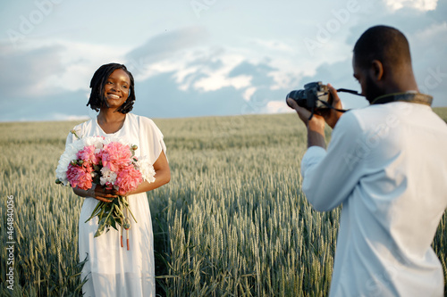 Happy couple with camera at summer field