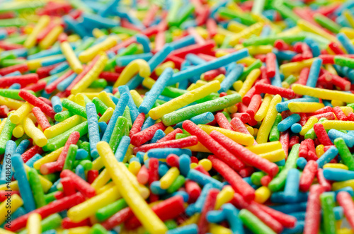Sugar paste for decoration, background, top view. Rainbow sprinkle for confectionery. Colorful confetti, background, top view. Pile of confectionery sprinkles, top view. Confectionery decor.