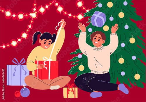 Girls sitting beside christmas tree playing with their gift boxes.