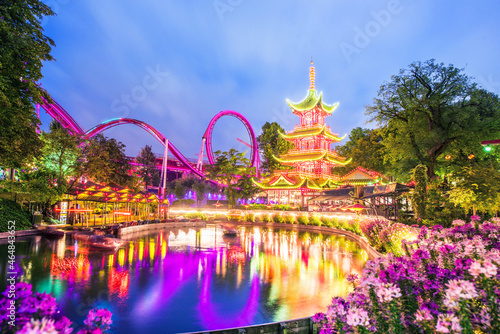 breathtaking magical landscape in Tivoli Gardens in the evening with rides in the illuminations. Copenhagen, Denmark. Exotic amazing places. Popular tourist atraction.