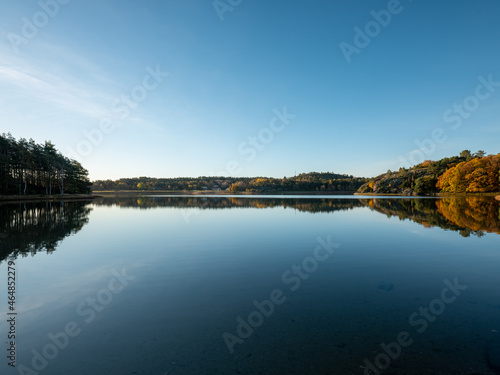 Calm water with autumn color trees reflecting in wide scene. Shot in Sweden, Scandinavia