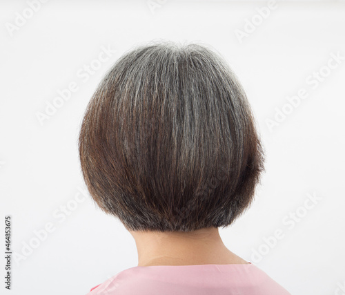 Head of elderly woman transforming to grey hair, from behind on white background