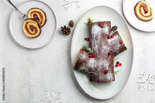 Traditional Christmas cake. Yule log or Buche de Noel. Sponge cake with chocolate cream, ganache, decorated with cranberries. Directly above, copy space.