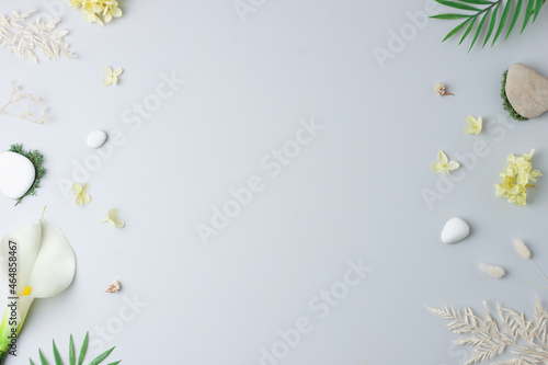 Cosmetic background with flowers, moss and stone on grey. Flat lay, copy space