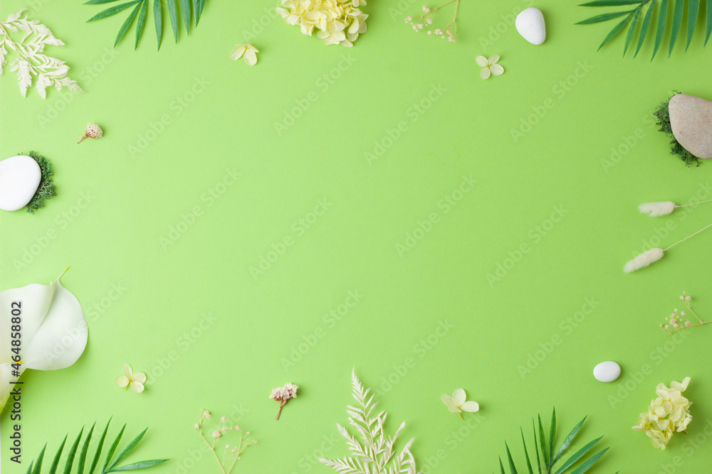 Cosmetic background with flowers, moss and stone on green. Flat lay, copy space