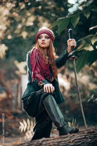 Outdoor portrait of young female in pirate costume with a sword.