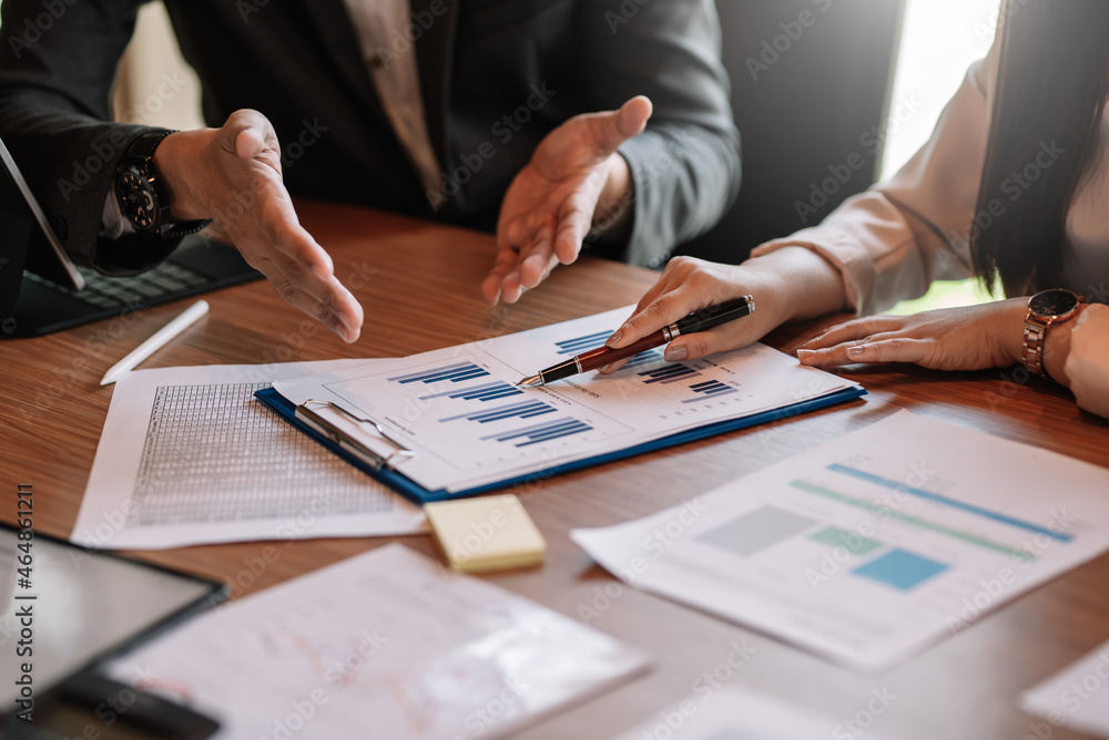 Close up view of business people investment advisors pointing at graph and analyzing financial report in meeting. Close up view of business people investment advisors pointing at graph and analyzing financial report in meeting.