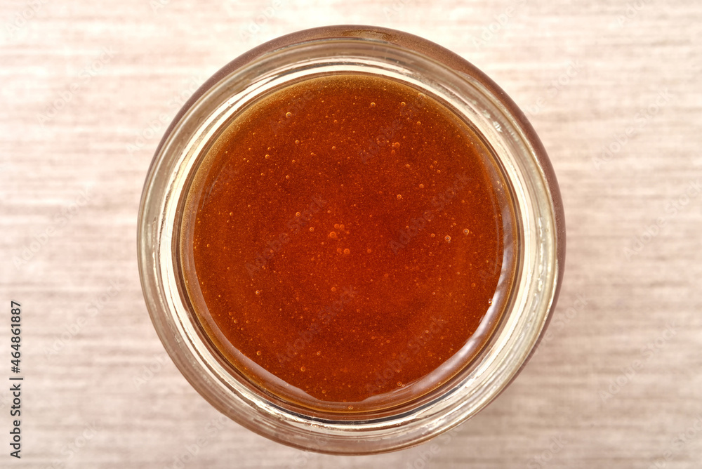 Sweet natural honey in a glass jar on the rustic wooden table. Close-up photo. Top view. Healthy food concept. 