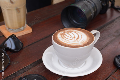 Top view of hot latte with camera and glasses on side. Work in a coffee shop. cappuccino with latte art: Pasuruan, Indonesia - August 28, 2020 photo