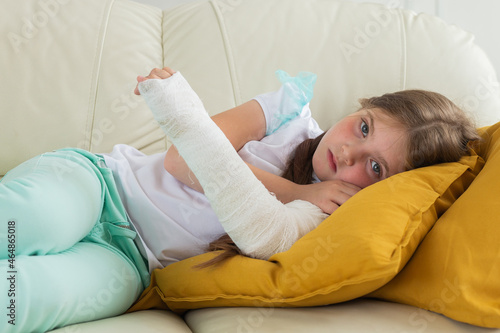 Child with a cast on a broken wrist or arm lying on a couch. Recovery and disease concept.