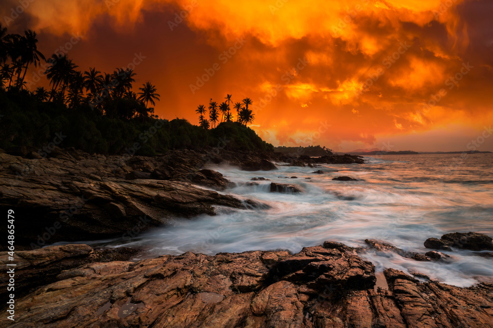 Obraz premium Sunset on the rocky shore of tropical sea