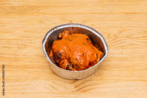 Whole charcoal-roasted chicken with mojo picon sauce on top in aluminum takeaway container photo