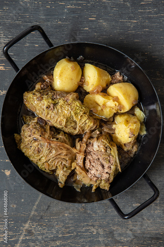 mit Hackfleisch gefüllte und Wirsing umwickelte Roulade auf dunklem Tisch aus Holz mit Kartoffeln als Beilage	