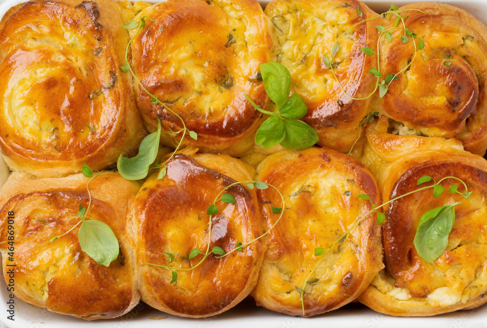 Buns with feta cheese and basil of yeast dough on a light wooden background. Selective focus. Rustic style.Top view Buns with feta cheese and basil of yeast dough on a light wooden background. Selective focus. Rustic style.Top view