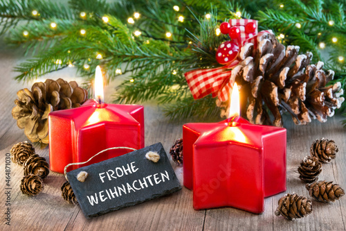 Frohe Weihnachten und Dekoration mit Schild und zwei Kerzen auf Holz