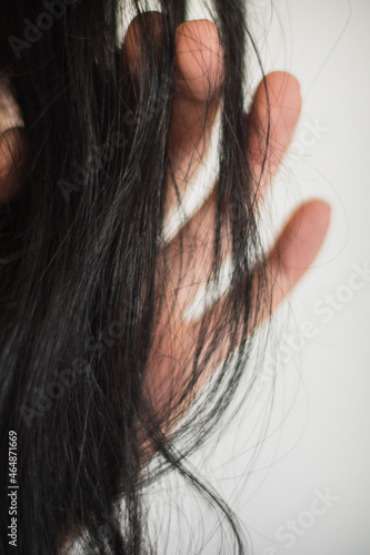 Mano y partes de la piel de una mujer junto con su pelo negro y lunares. photo