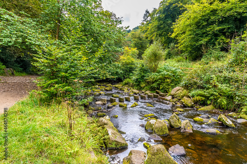A view along Hebden Beck towards stepping stones on the outskirts of Hebden Bridge, Yorkshire, UK in summertime