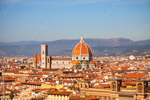 Santa Maria del Fiore cathedral in Florence, Italy. Aereal panoramic view with dome by Filippo Brunelleschi, and bell tower dominating the skyline in Tuscany, Italy. Mountains and blue sky background.
