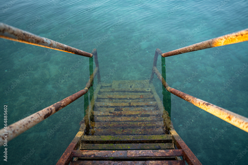 Fototapeta premium Rusty iron stairs into the blue sea