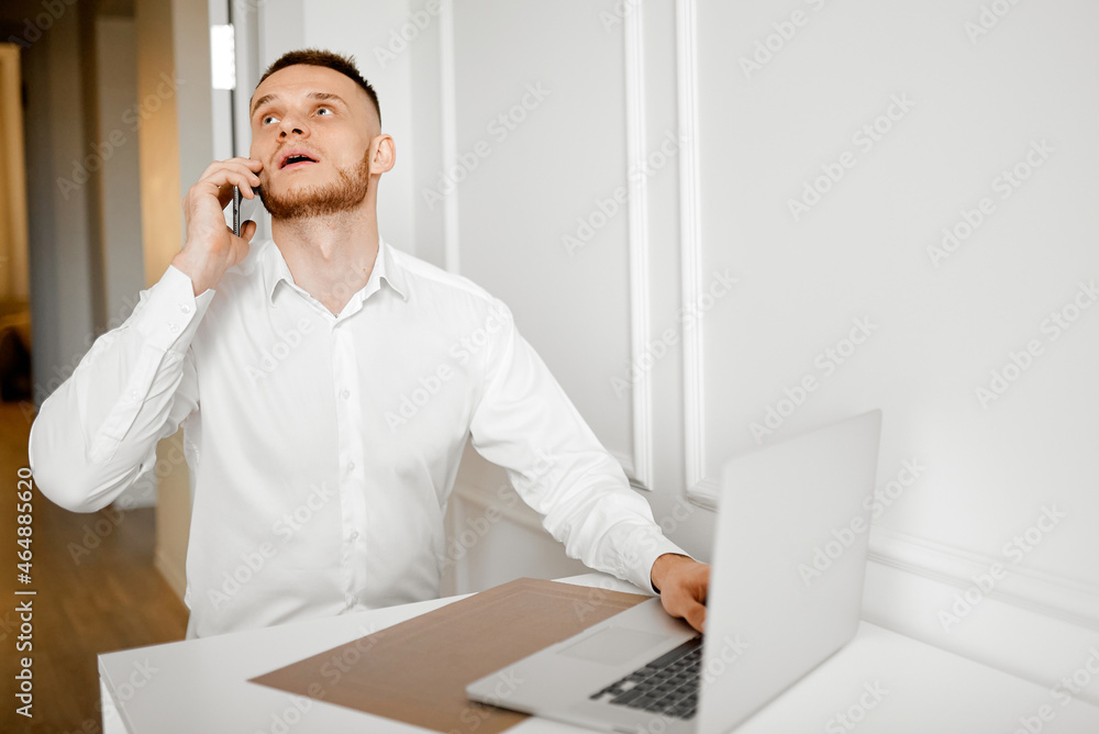 A young man working in the kitchen talking on the phone thought A young man working in the kitchen talking on the phone thought