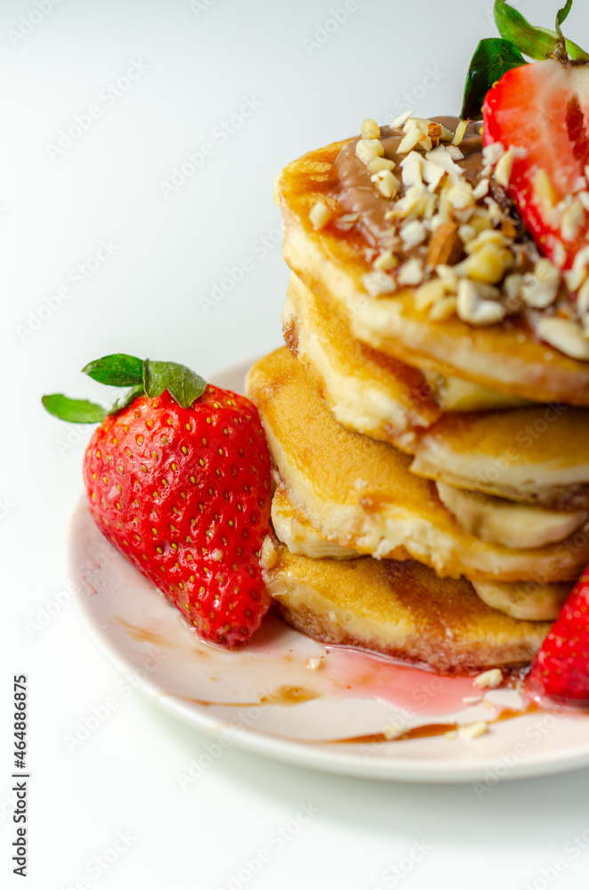 Pancakes stacked with bananas, strawberries and nuts, topped with chocolate and strawberry sauce Pancakes stacked with bananas, strawberries and nuts, topped with chocolate and strawberry sauce
