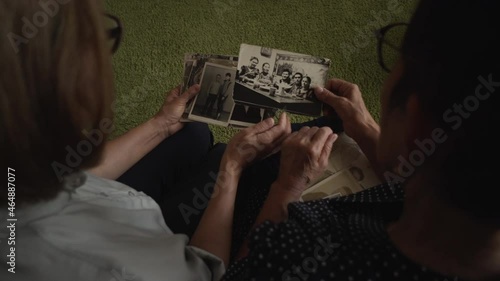 Mature daughter visits senior mother and watching family photo album