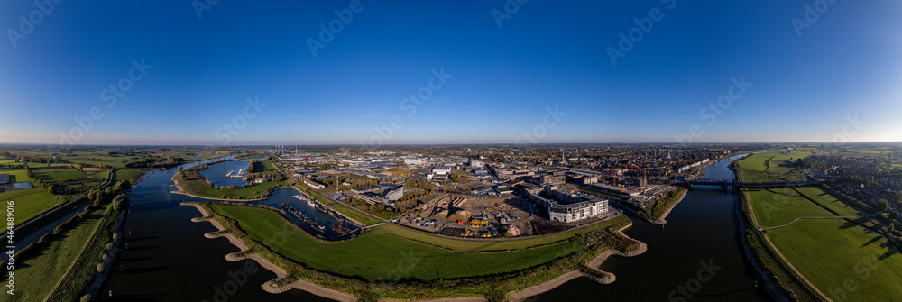 PUUR21 construction site aerial with wide view of Noorderhaven neighbourhood along the river IJssel against a clear blue sky. Urban development in tower town Zutphen.