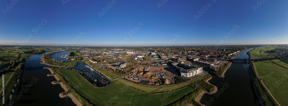 Obraz premium Construction site PUUR21 aerial with wide view of Noorderhaven neighbourhood along the river IJssel against a clear blue sky. Urban development in tower town Zutphen, The Netherlands.