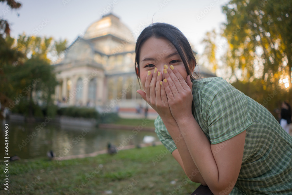 lifestyle portrait of young happy and attractive Asian Chinese woman relaxed taking a walk on city park enjoying travel getaway in Spain during Autumn holidays travel