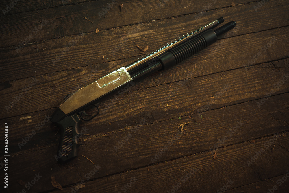 Naklejka premium Pump-action shotgun on the wooden floor in the house. Criminal showdowns. Problems with the storage of weapons.