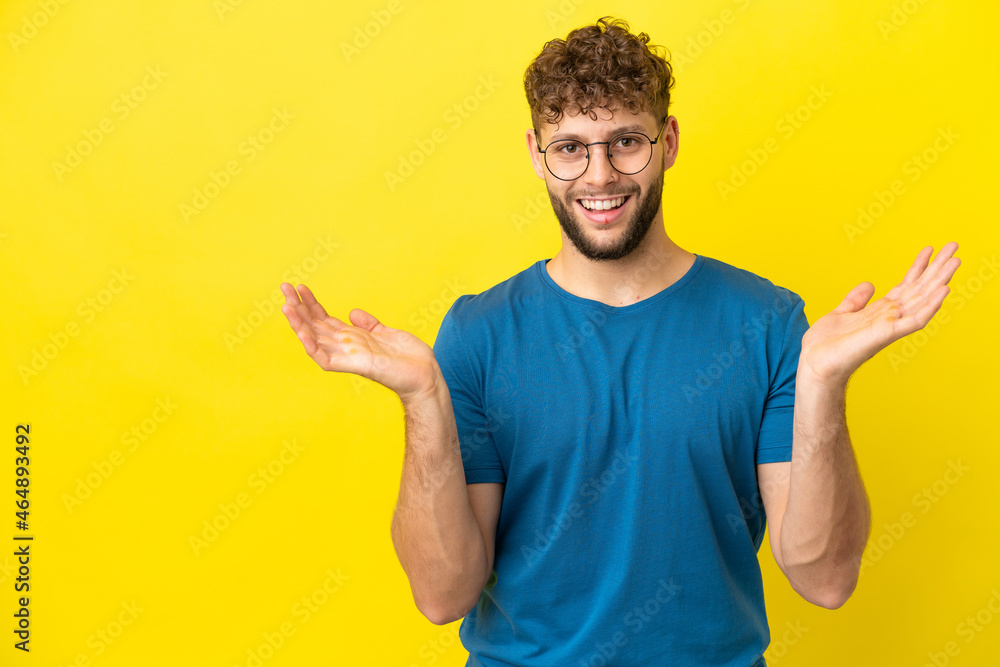 Young handsome caucasian man isolated on yellow background with shocked facial expression Young handsome caucasian man isolated on yellow background with shocked facial expression