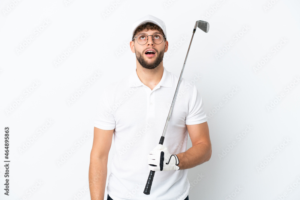 Handsome young man playing golf isolated on white background looking up and with surprised expression Handsome young man playing golf isolated on white background looking up and with surprised expression