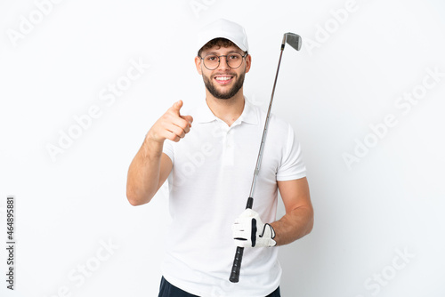 Handsome young man playing golf isolated on white background surprised and pointing front