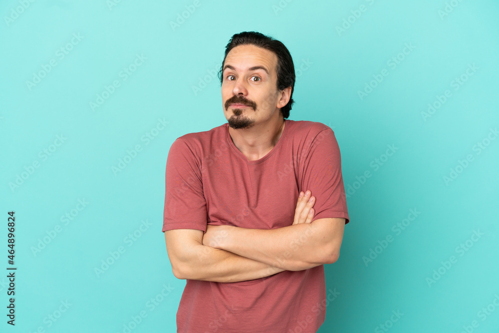 Young caucasian man isolated on blue background making doubts gesture while lifting the shoulders Young caucasian man isolated on blue background making doubts gesture while lifting the shoulders