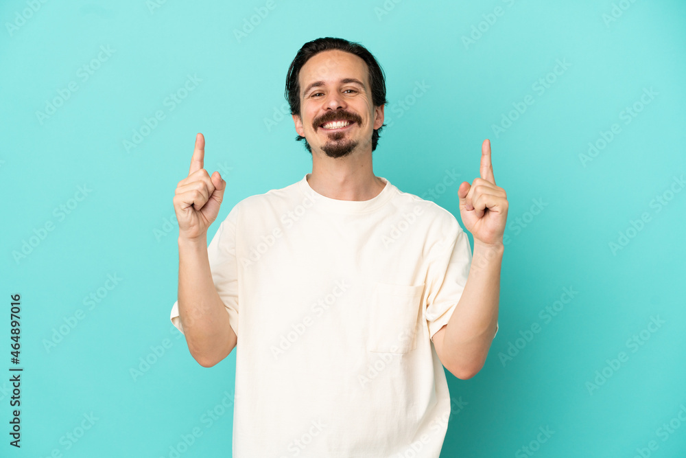 Young caucasian man isolated on blue background pointing up a great idea Young caucasian man isolated on blue background pointing up a great idea