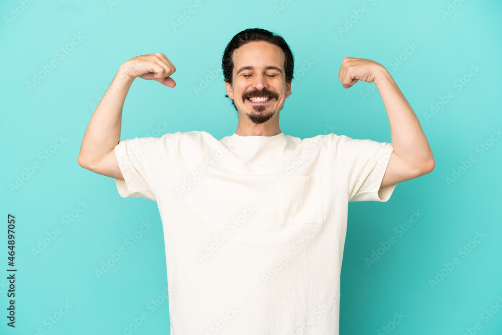 Young caucasian man isolated on blue background doing strong gesture Young caucasian man isolated on blue background doing strong gesture