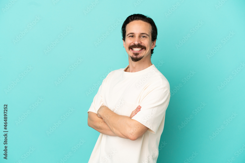 Young caucasian man isolated on blue background with arms crossed and looking forward Young caucasian man isolated on blue background with arms crossed and looking forward