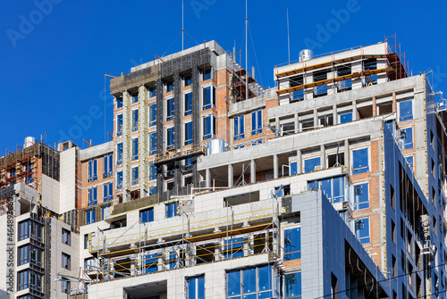 Modern construction of a high-rise residential building with the concept of insulation and facade decoration.