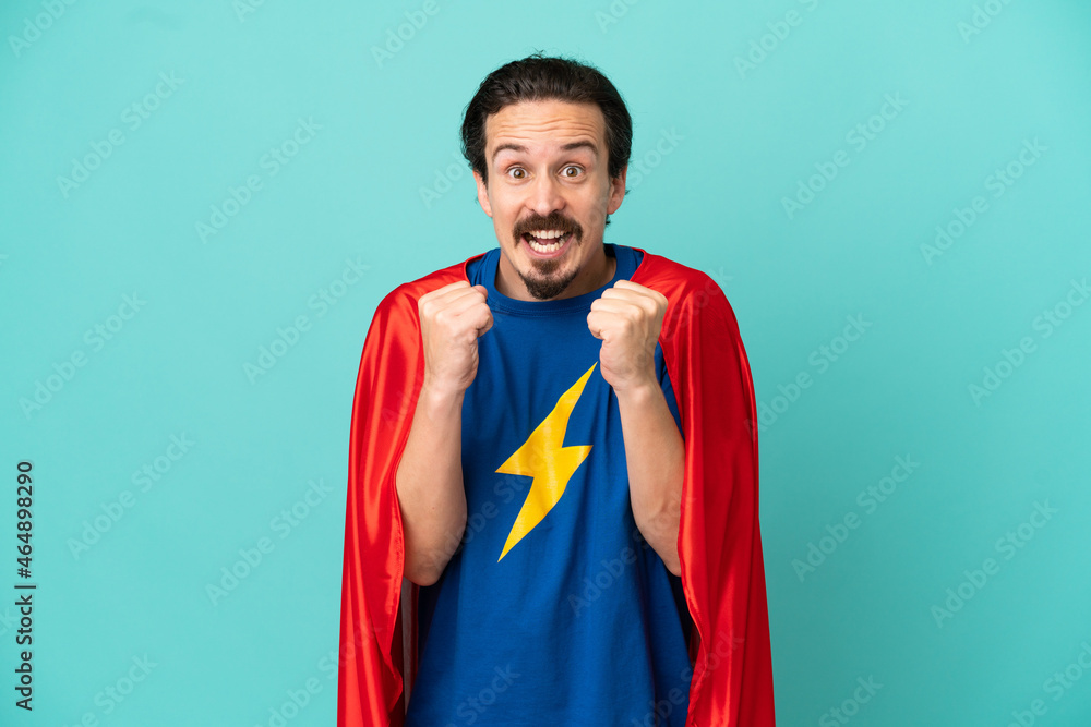 Super Hero caucasian man isolated on blue background celebrating a victory in winner position Super Hero caucasian man isolated on blue background celebrating a victory in winner position