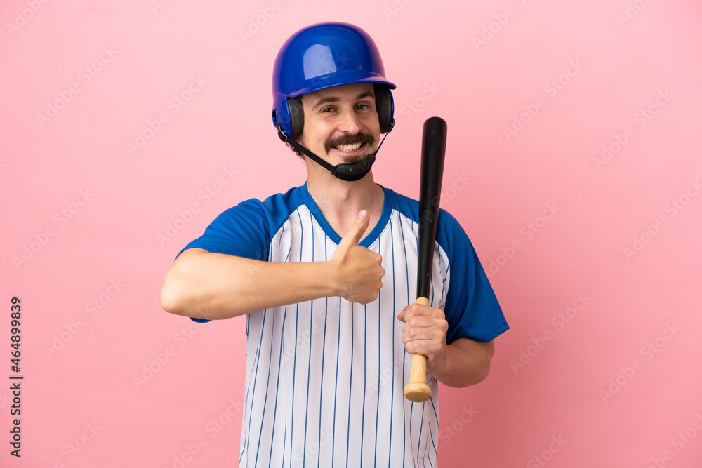Young caucasian man playing baseball isolated on pink background giving a thumbs up gesture
