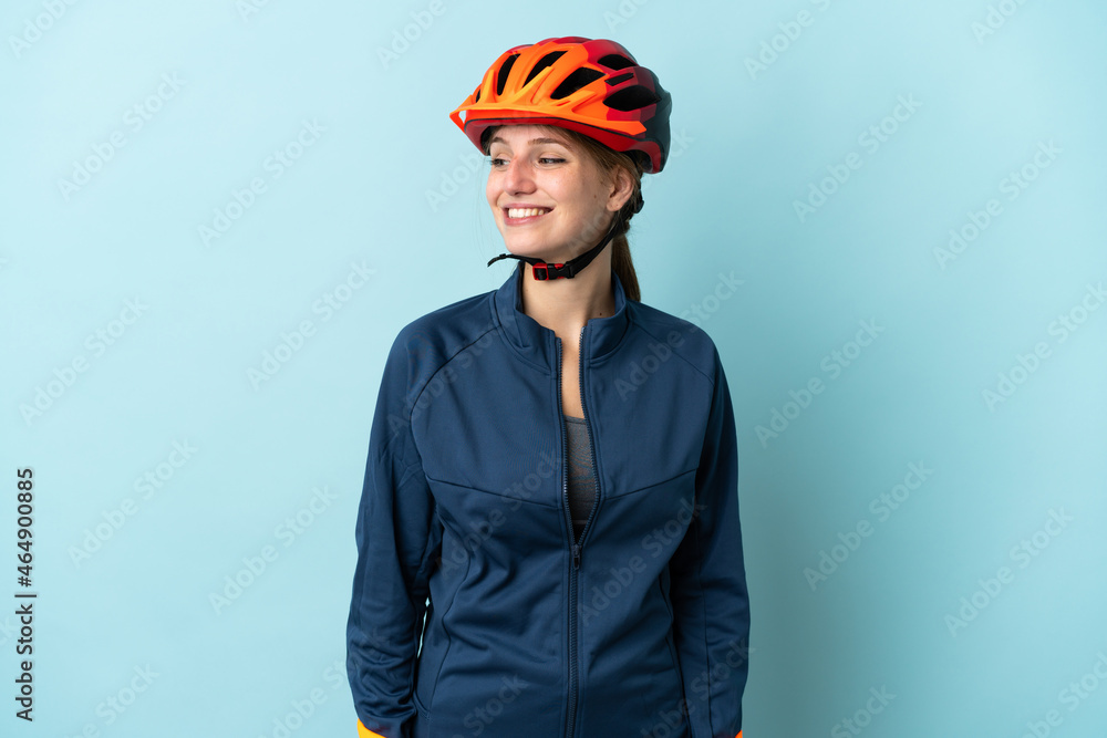 Young cyclist woman isolated on blue background looking to the side and smiling Young cyclist woman isolated on blue background looking to the side and smiling