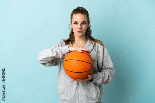 Young caucasian woman isolated on blue background playing basketball © luismolinero