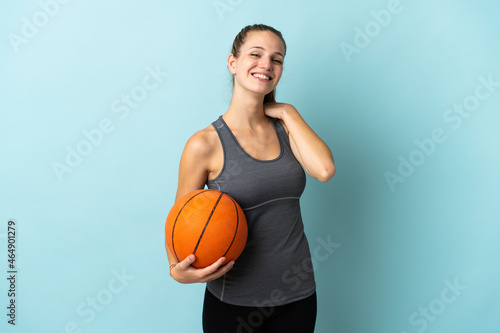 Young woman playing basketball isolated on blue background laughing