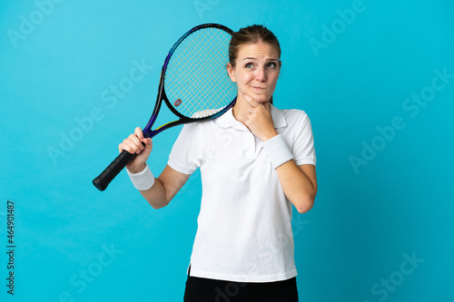 Young woman tennis player isolated on blue background having doubts and thinking © luismolinero