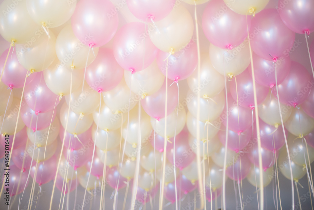 Softly celebrating background. Pink and light yellow balloons under ceiling. Some blur