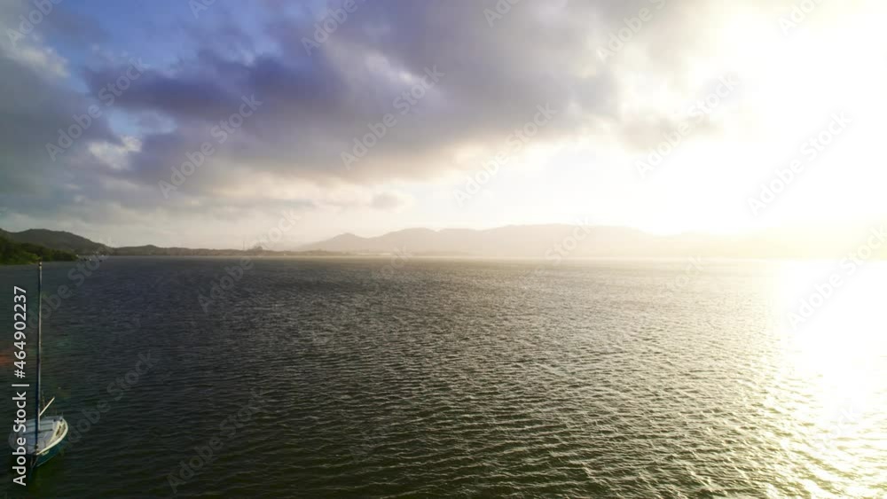 A floating boat in the ocean meets the sunset with the mountains on the horizon. A floating boat in the ocean meets the sunset with the mountains on the horizon.