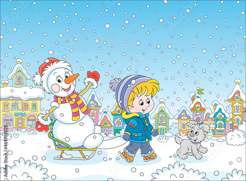 Happy little boy walking with his merry pup and sledding a funny snowman down a snow-covered street of a pretty small town on a beautiful snowy winter day, vector cartoon illustration