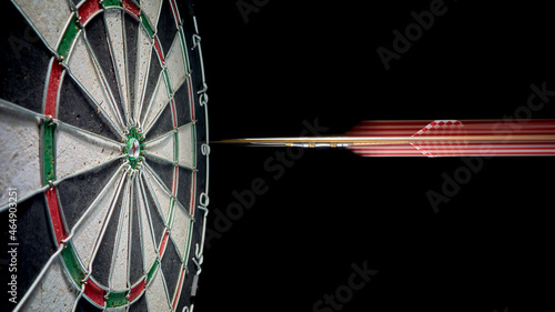 The dart flies into the bullseye dartboard. Blurred dart trail. photo